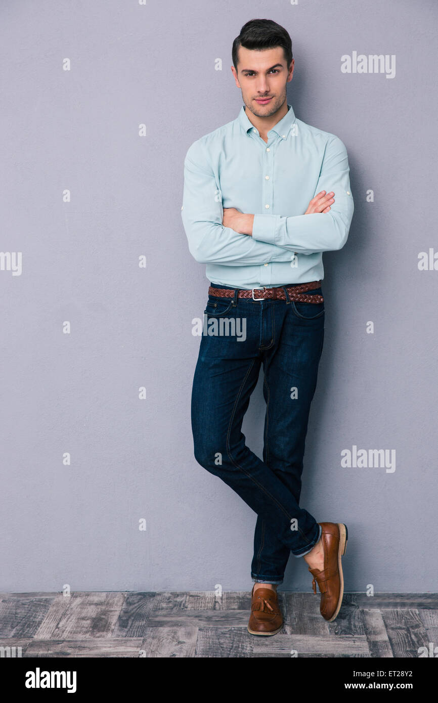 Full length portrait of a handsome young man standing with arms folded ...