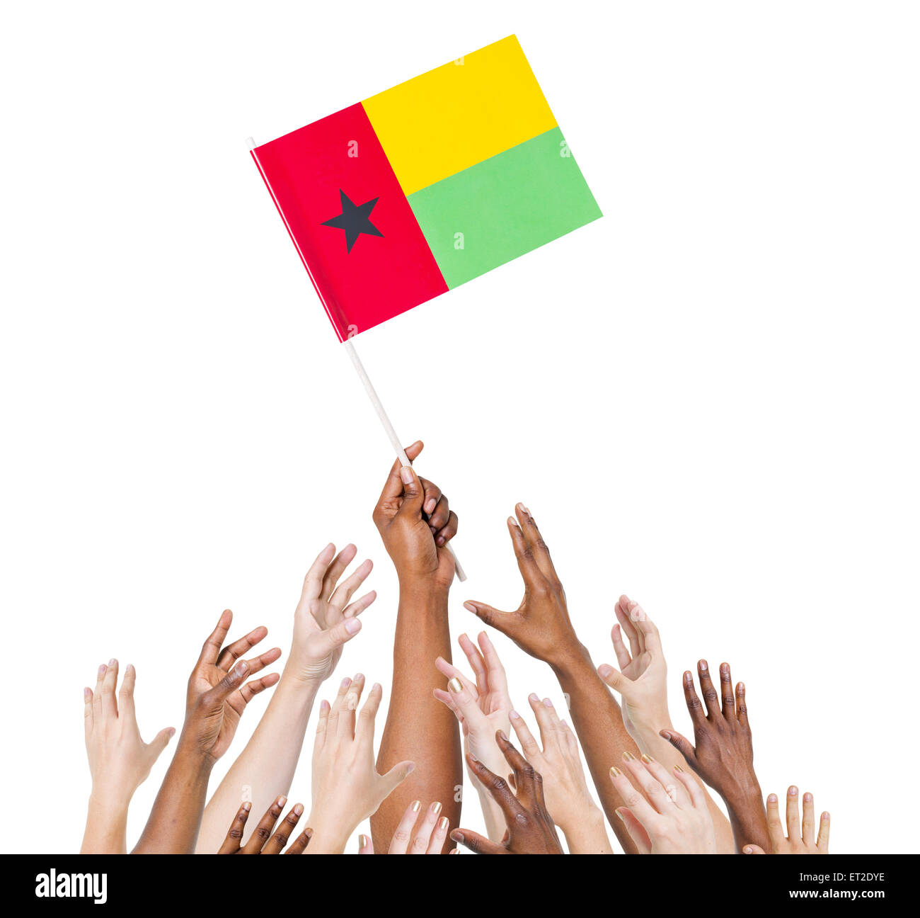 Group of multi-ethnic people reaching for and holding the flag of Guinea Bissau. Stock Photo