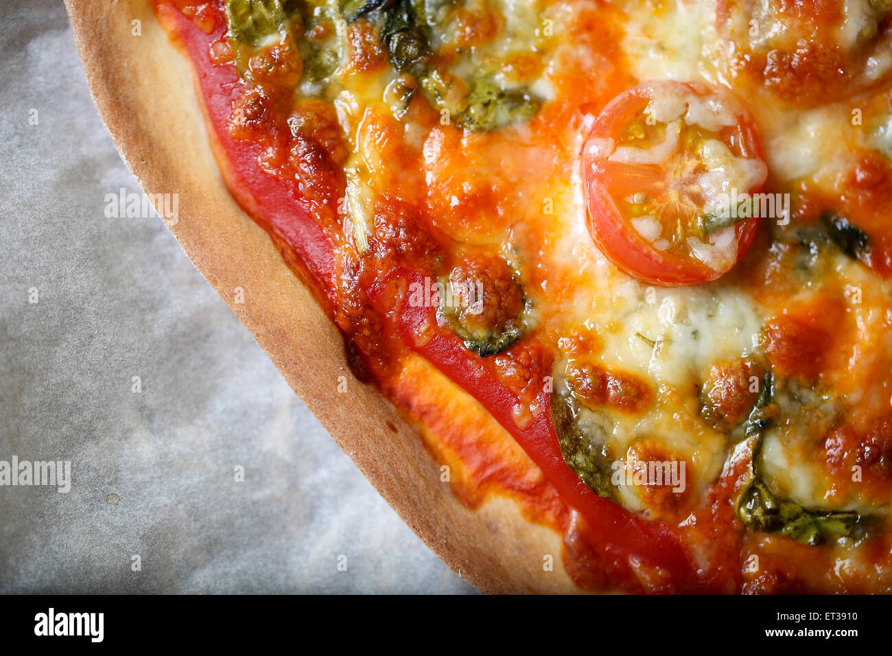 Traditional home made thin crust pizza with spinach, tomato, and mozzarella Stock Photo