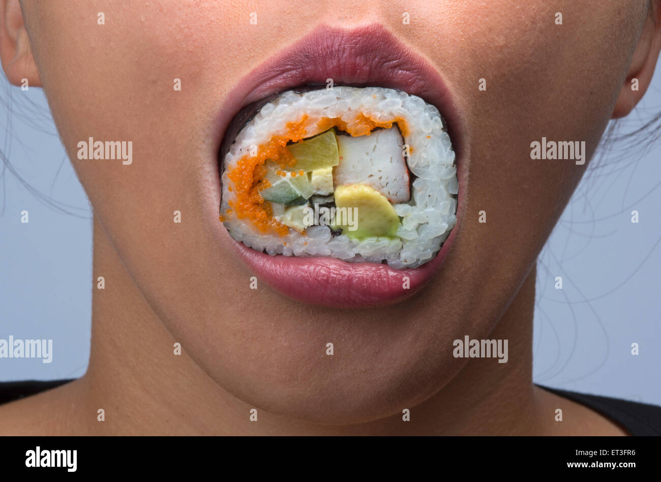 woman eating sushi having sushi in her mouth Stock Photo