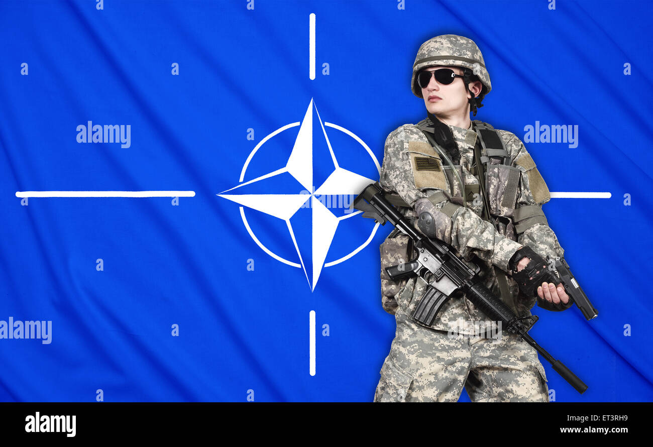 US soldier with gun on a Nato flag background Stock Photo