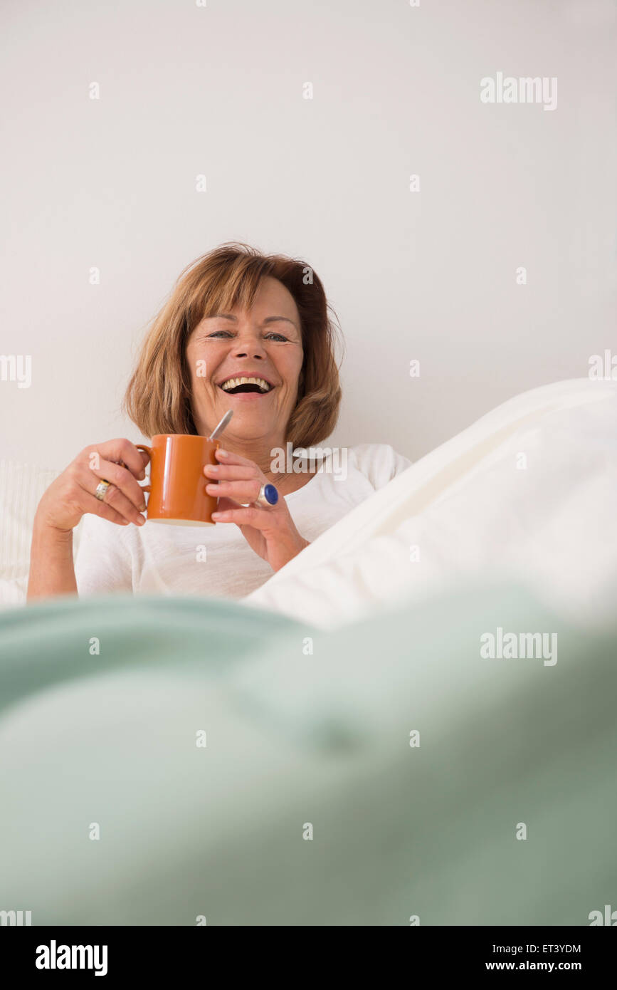 Senior woman at her bedroom drinking tea in the morning, Munich