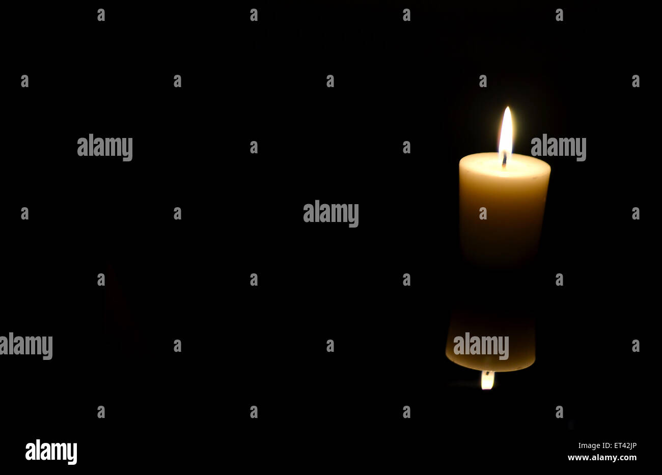Small candle in the black pitch darkness. Stock Photo