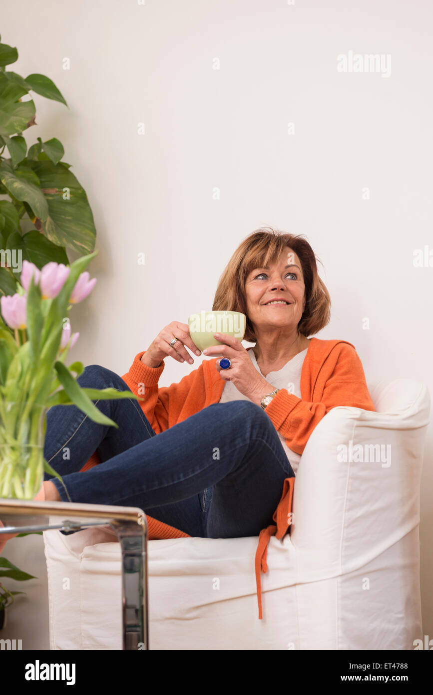 Senior woman dreaming while drinking tea at home, Munich, Bavaria