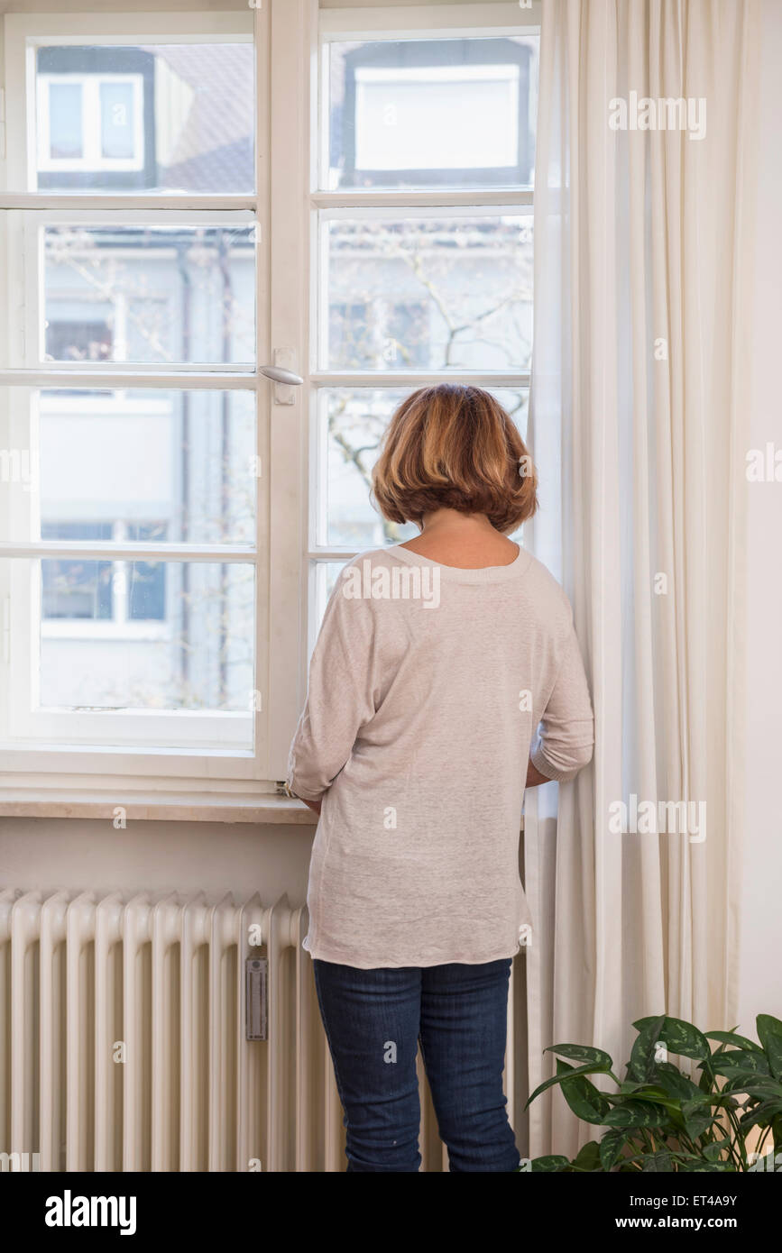 Rear view of senior woman looking through a window, Munich, Bavaria, Germany Stock Photo