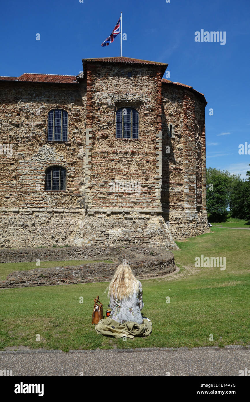 Girl sitting on grass in front of Colchester Castle, Essex Stock Photo