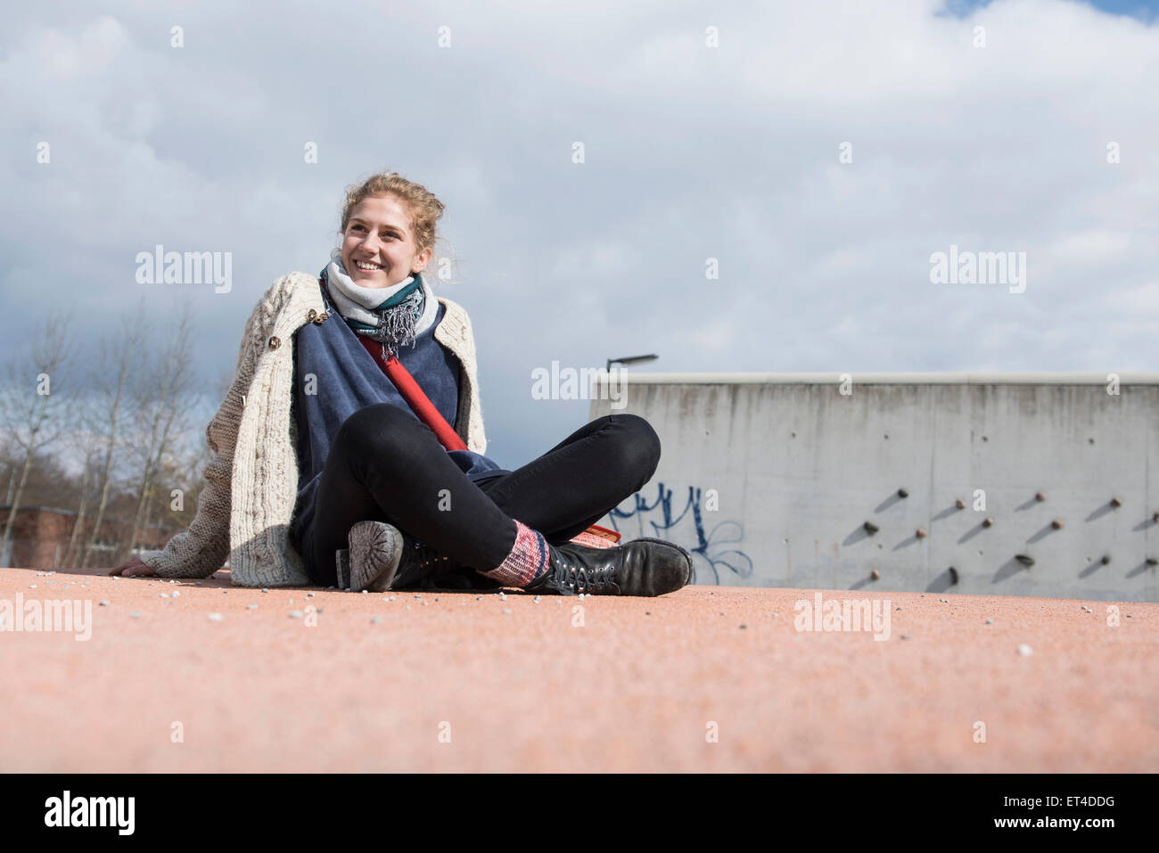 Young woman sitting cross-legged on playground turntable and smiling Munich Bavaria Germany Stock Photo