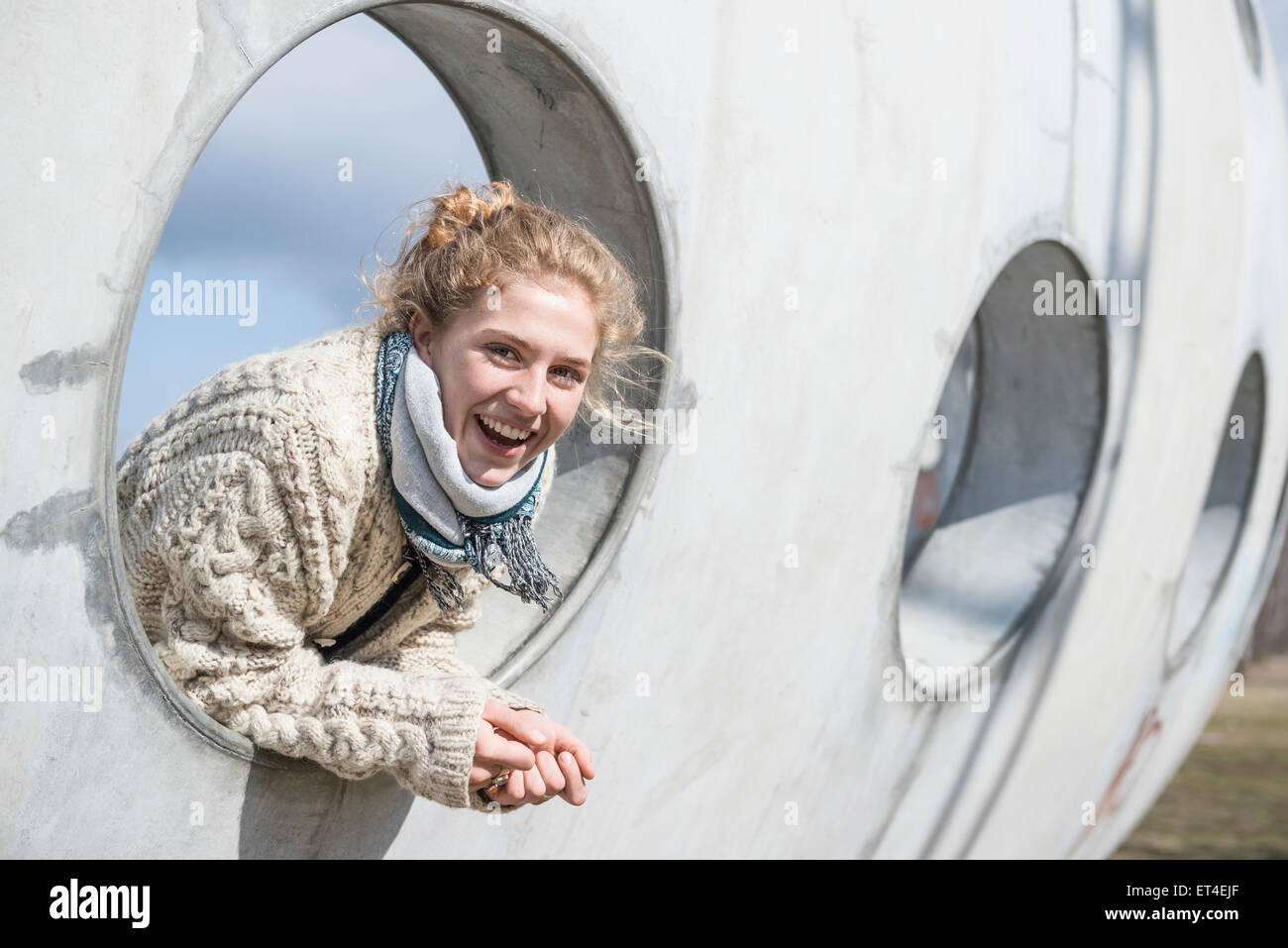 Young woman looking through a round hole in concrete wall Munich Bavaria Germany Stock Photo