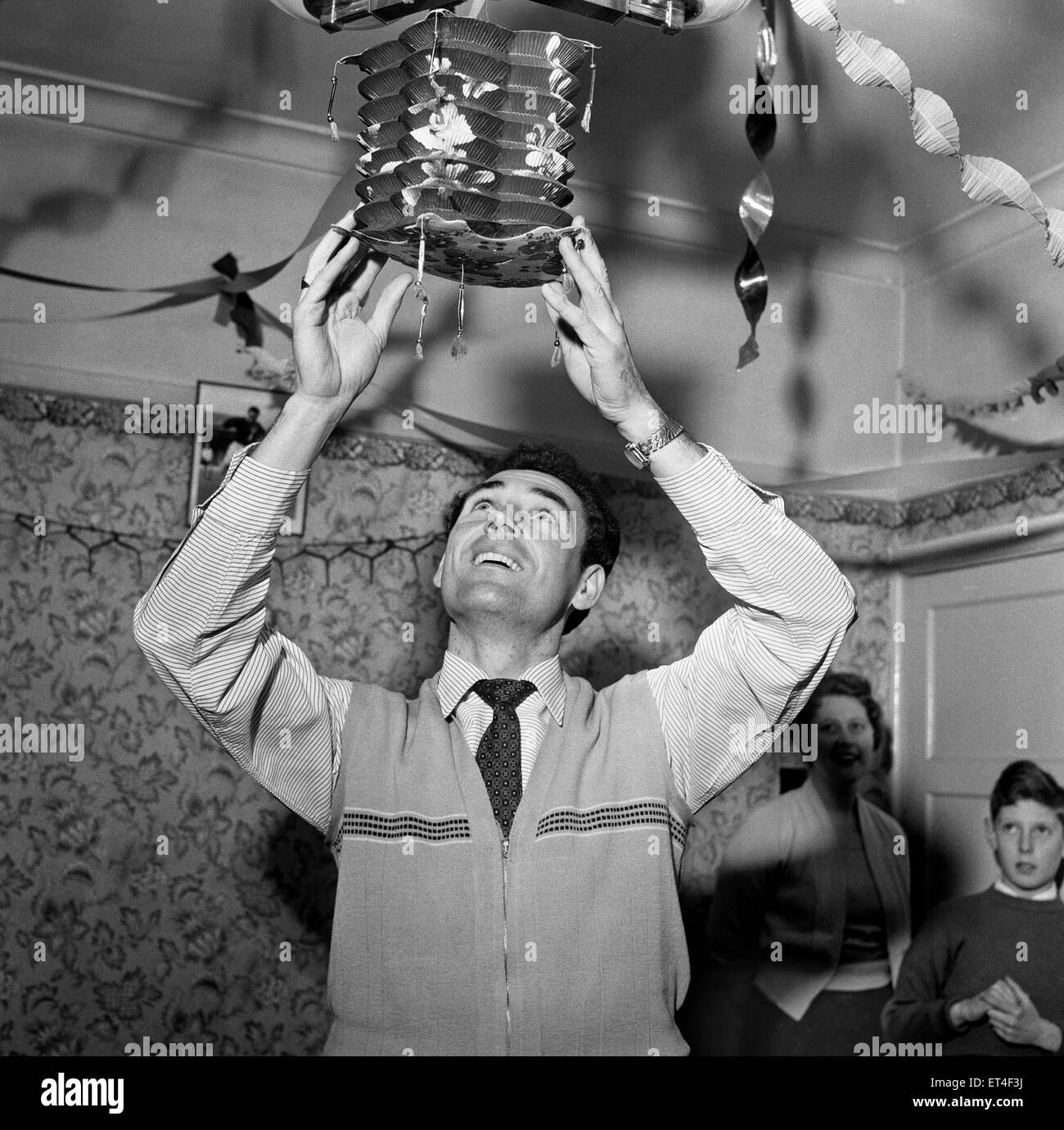 Charlton Athletic footballer Johnny Summers, who just scored five goals in one game in the spectacular fightback from 6-1 down to 7-6 winners against Huddersfield. Here he is pictured putting up the Christmas decorations at his home in Lewisham with wife and son. 22nd December 1957. Stock Photo