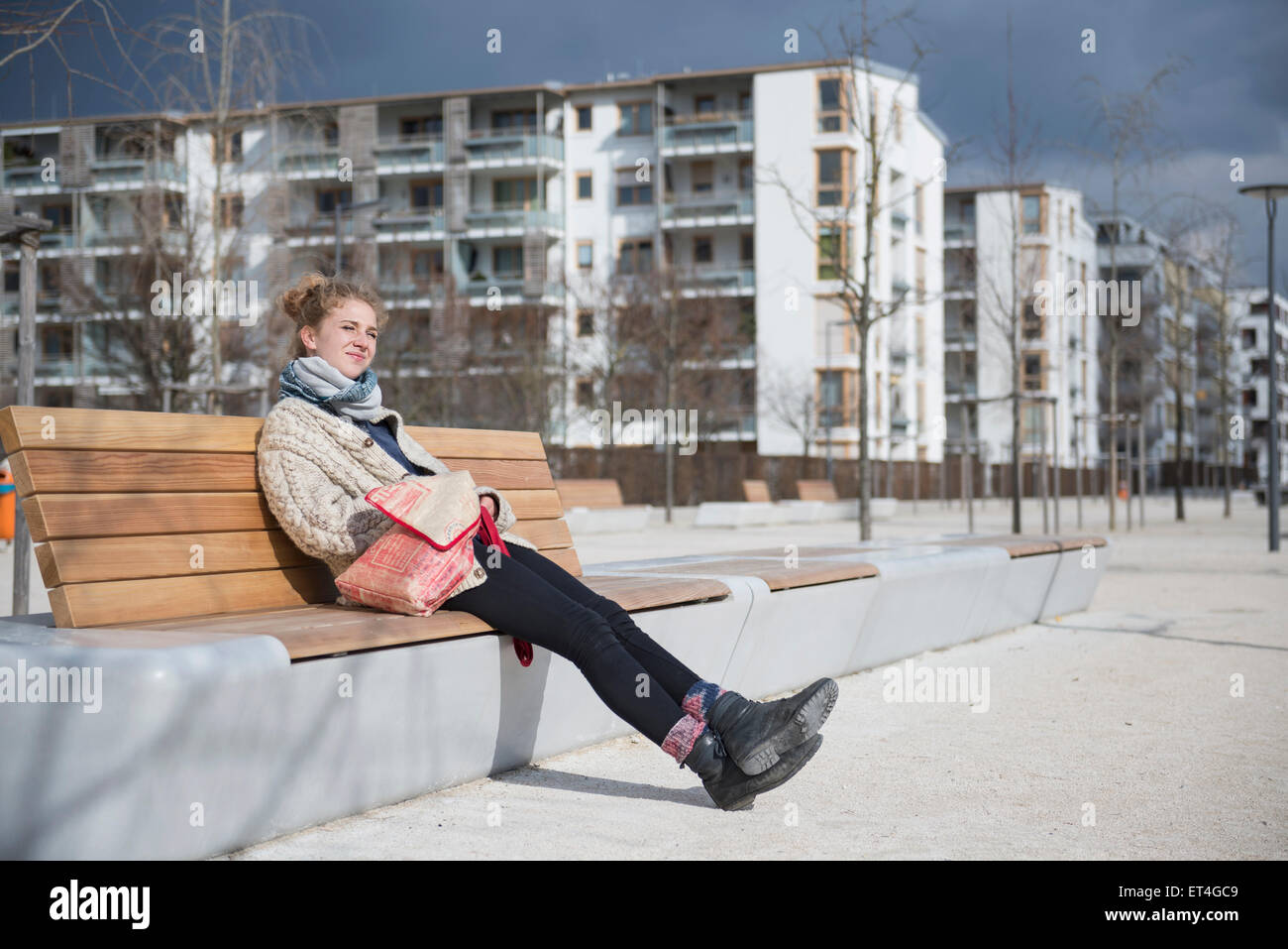 Young woman sitting on bench in city Munich Bavaria Germany Stock Photo