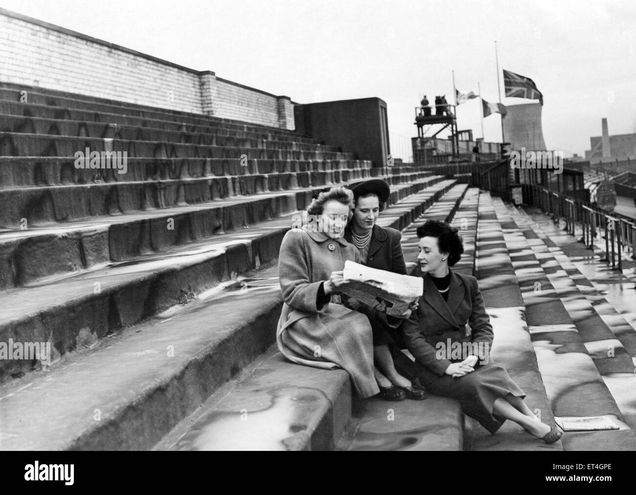 Three women checking the form in a newspaper at the Grand National race, Aintree Racecourse, Liverpool, Merseyside. 28th March 1953. Stock Photo