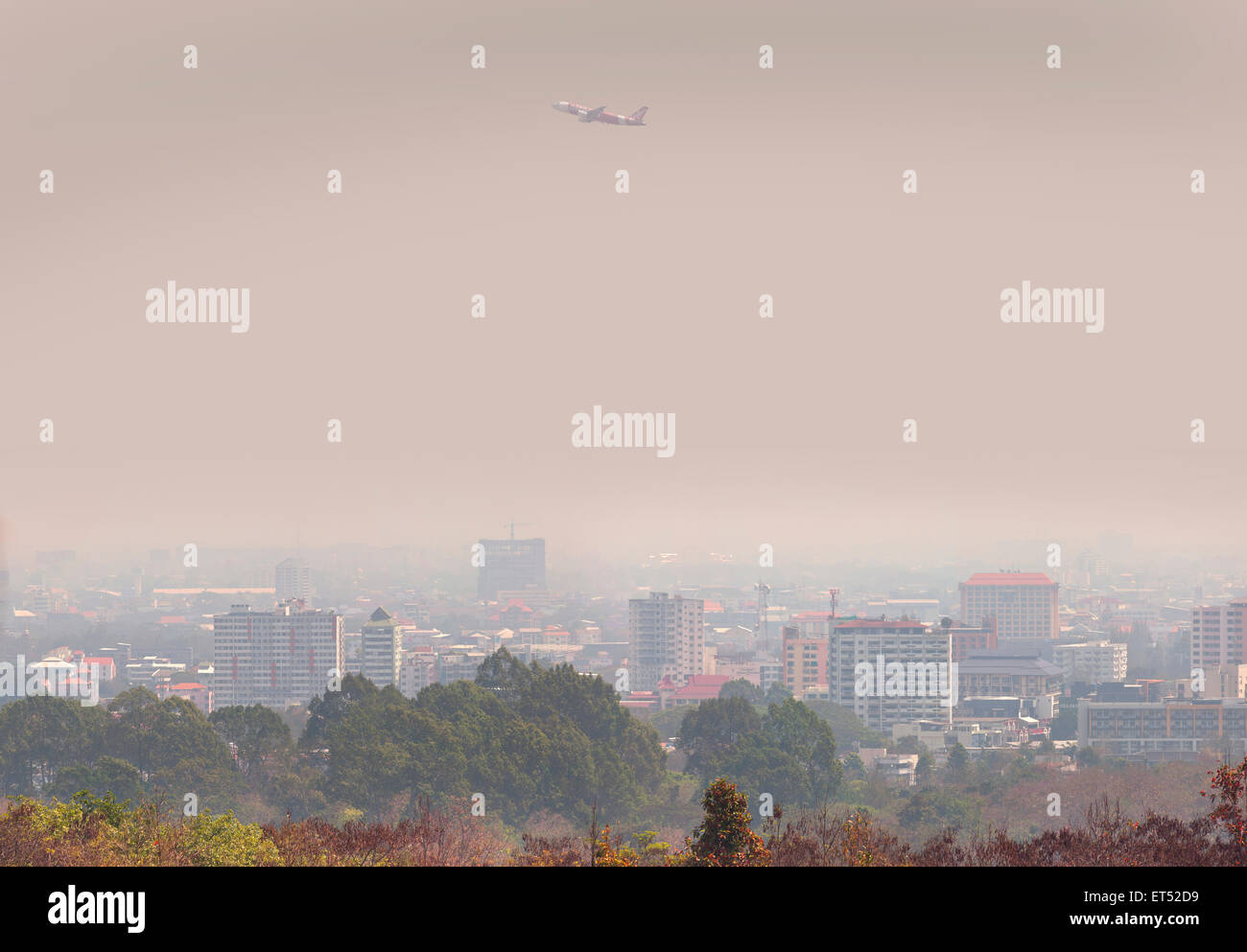 Air Asia passenger jet passes over Chiang Mai, Thailand, aerial pollution hangs over the city, smog Stock Photo