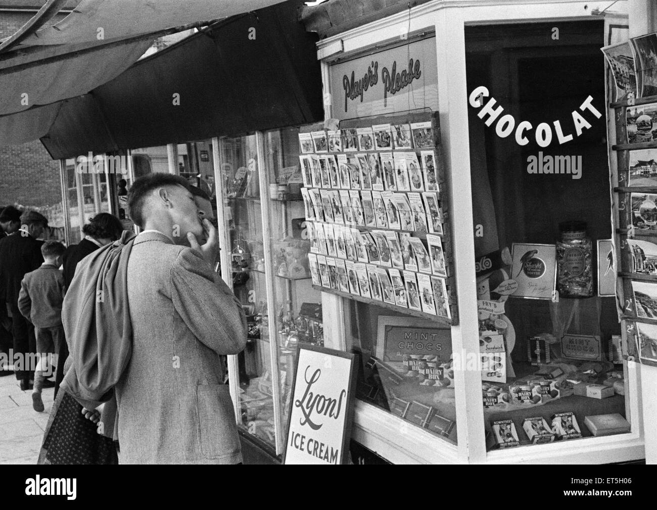 Holiday scenes at Hastings. Holidaymaker looking at saucy postcards in a newsagents window, East Sussex. June 1952. Stock Photo