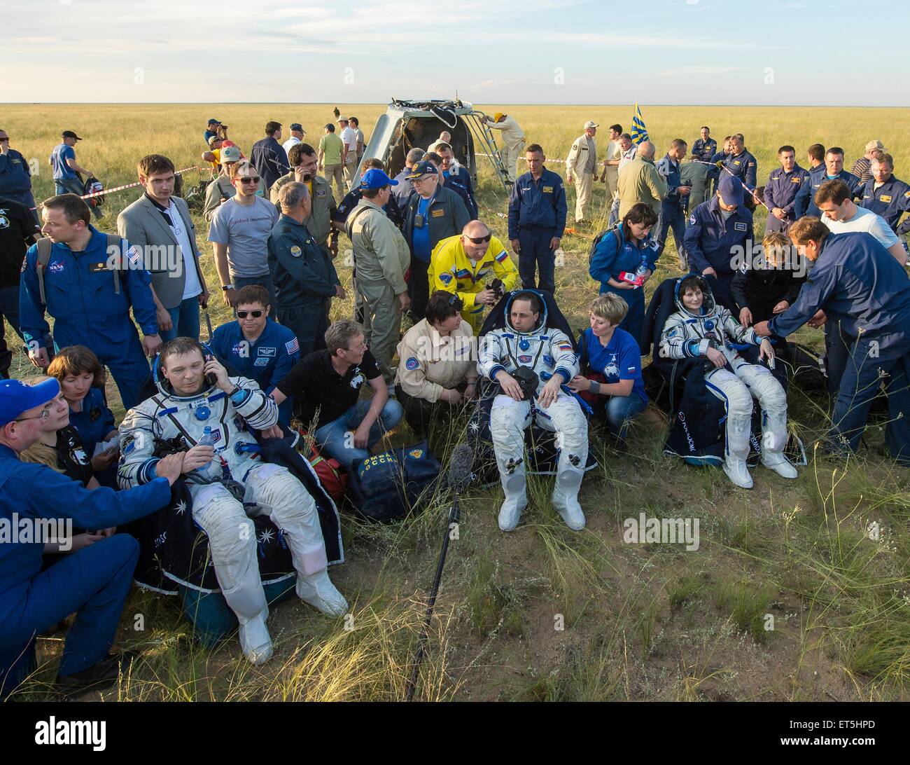 International Space Station Expedition 43 crew members commander Terry Virts of NASA and Cosmonaut Anton Shkaplerov of Roscosmos and Italian astronaut Samantha Cristoforetti from European Space Agency sit in chairs outside the Soyuz TMA-15M spacecraft just minutes after they landed in a remote area June 11, 2015 near Zhezkazgan, Kazakhstan. The crew is returning after more than six months onboard the International Space Station. Stock Photo
