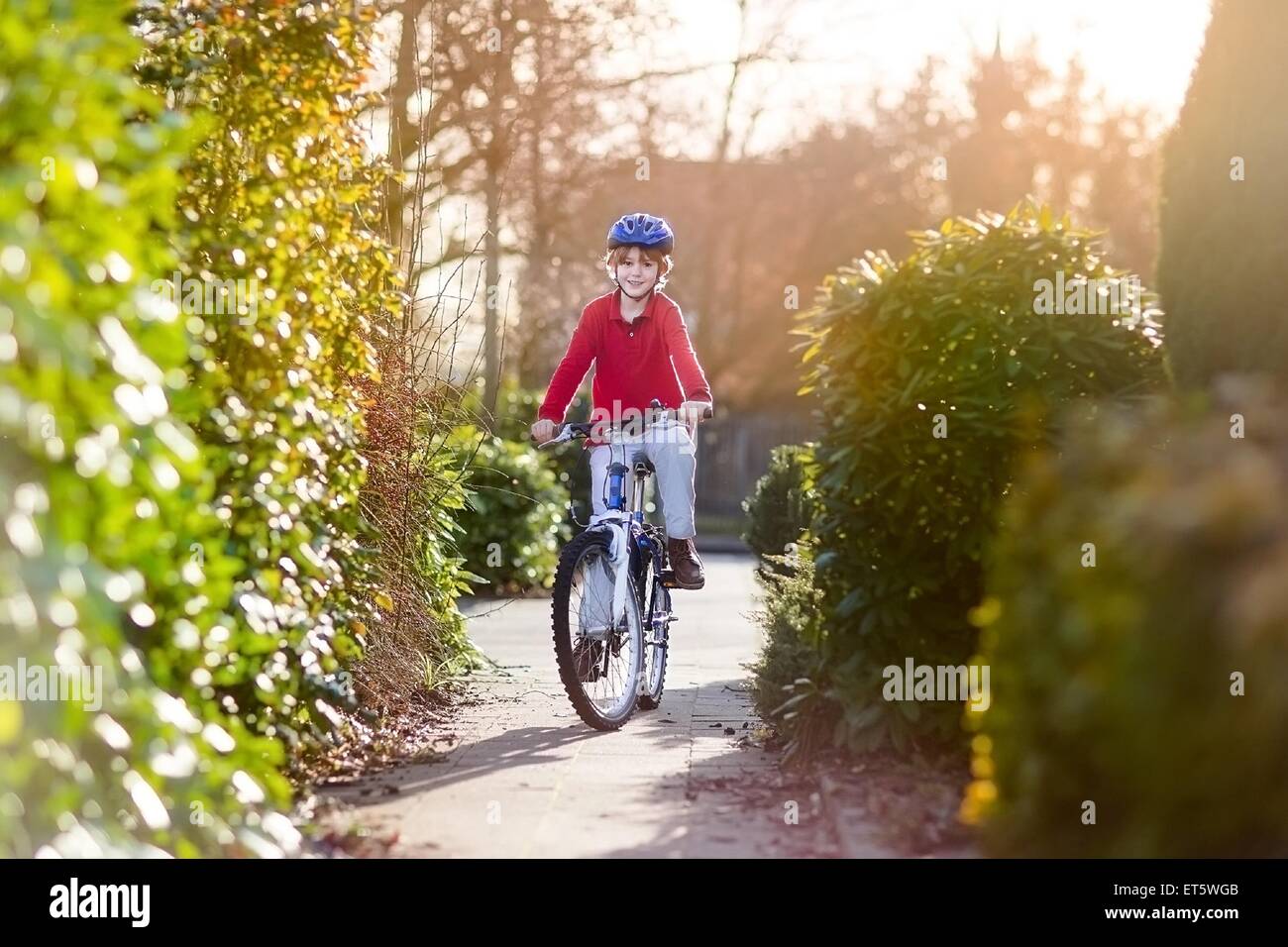 Happy smiling teenager boy riding his bike on sunset Stock Photo