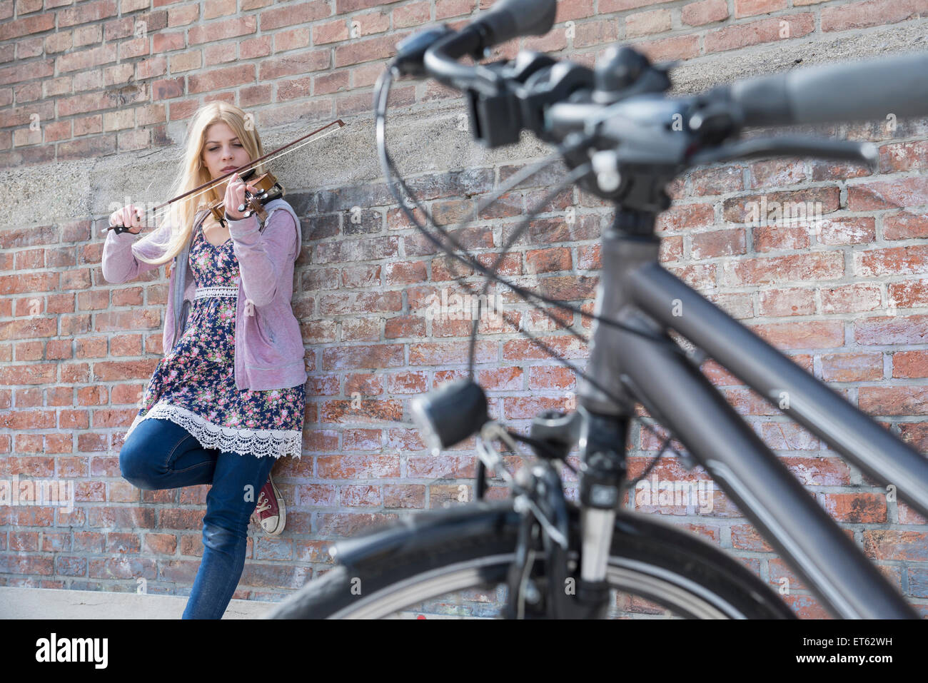 Caucasian teenage girl playing violin in front of brick wall, Munich ...