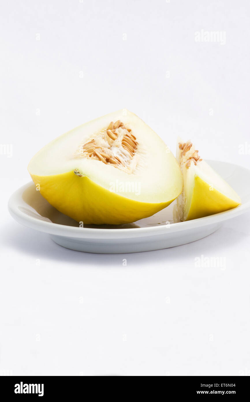 Canary melon sliced in a plate on white background Stock Photo