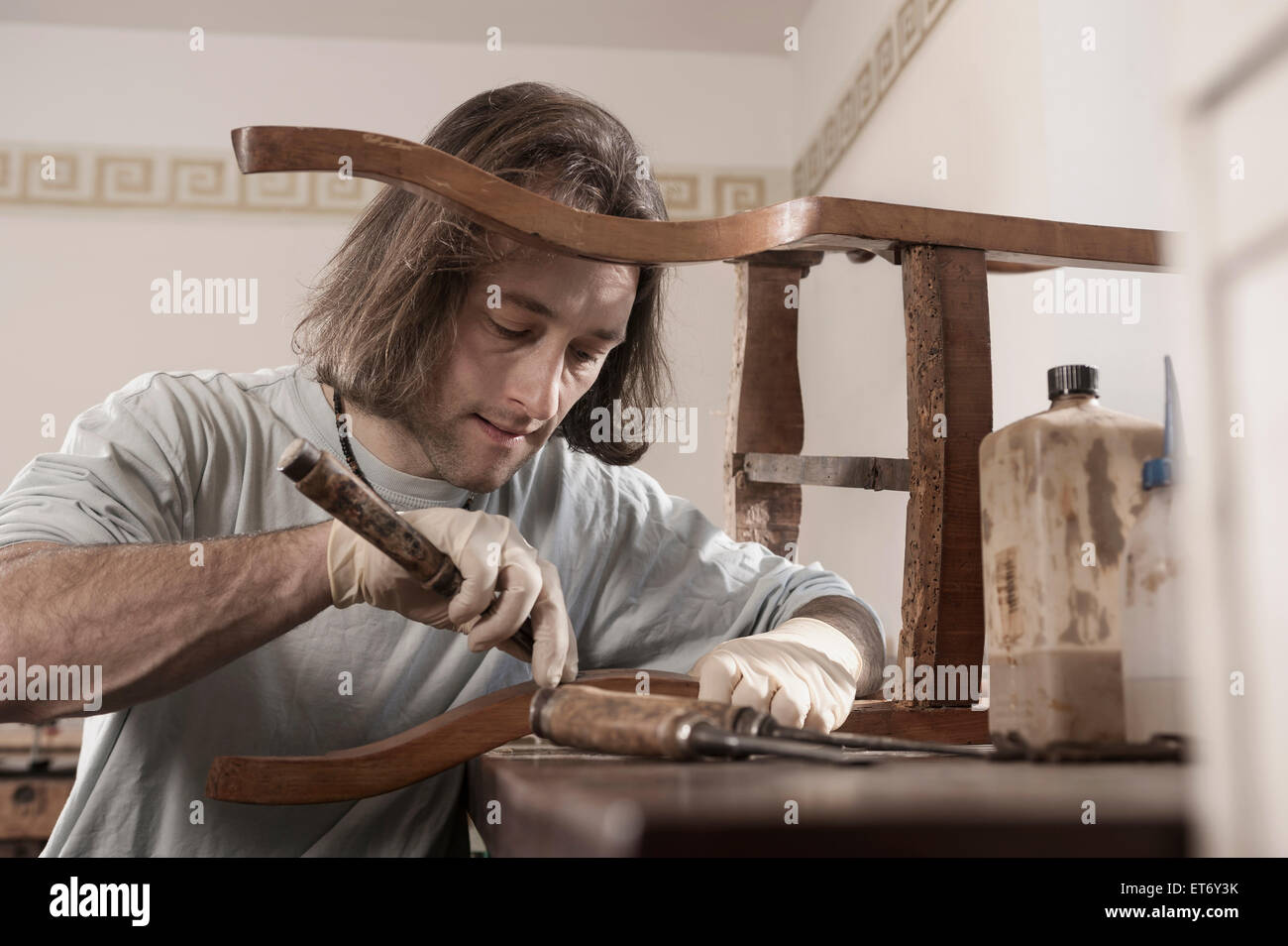 Carpenter repairing an antique wooden chair at workshop, Bavaria, Germany Stock Photo