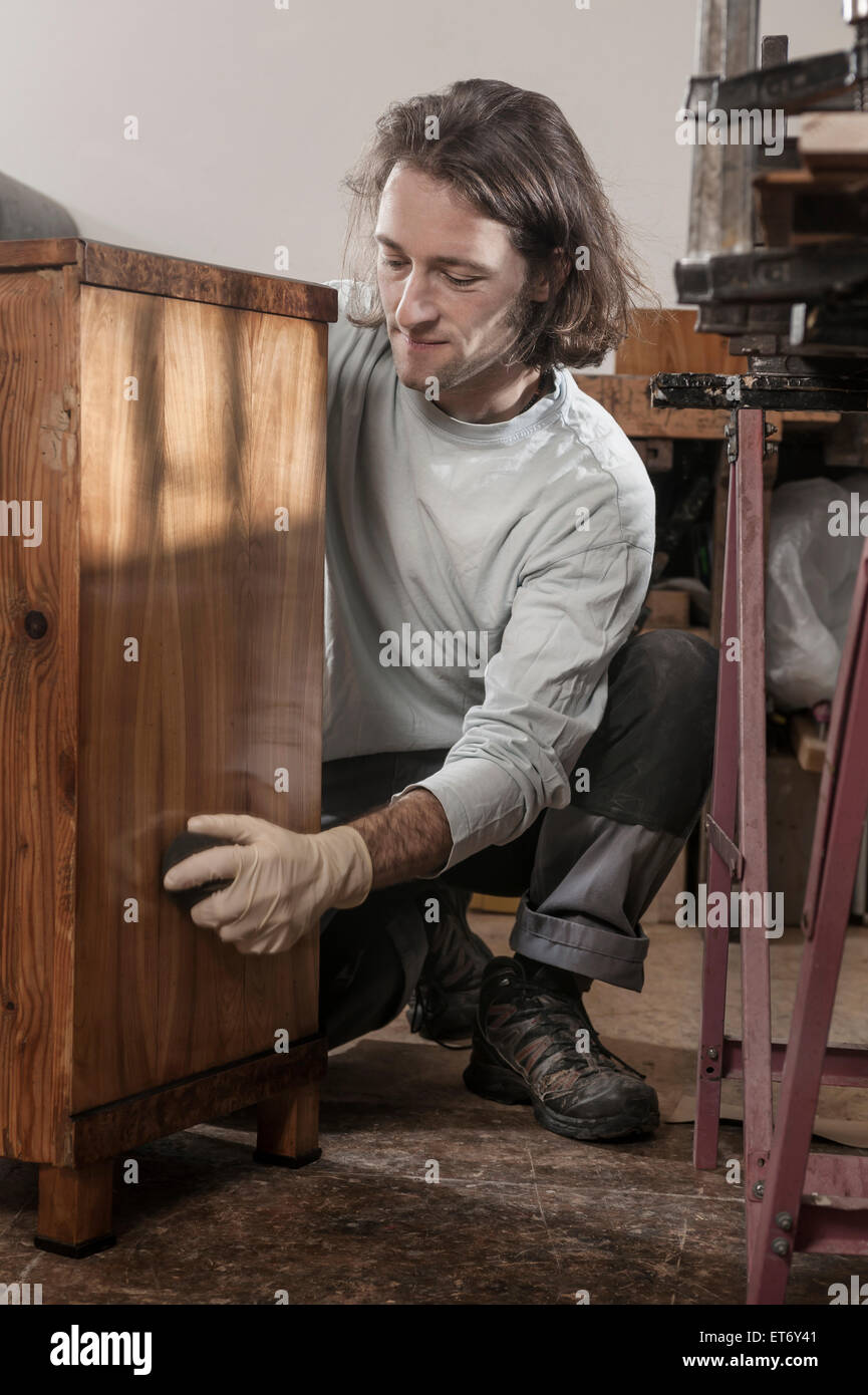 Carpenter French polishing on wooden drawer at workshop, Bavaria, Germany Stock Photo