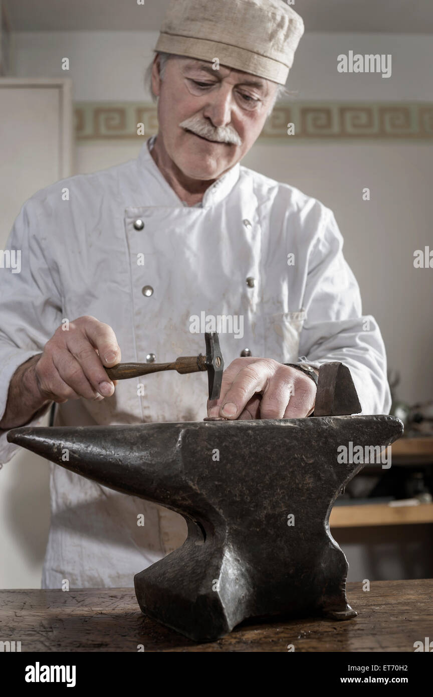 Senior craftsman shaping of copper ring at workshop, Bavaria, Germany Stock Photo