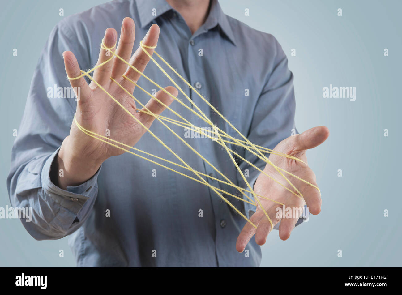 Mid section view of a man's hands making a cats cradle with string