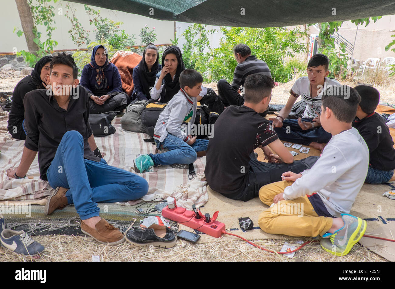 A group of Syrian and Afghani refugees await transport to the Lesvos island capital in a makeshift camp near Molyvos harbor. Stock Photo