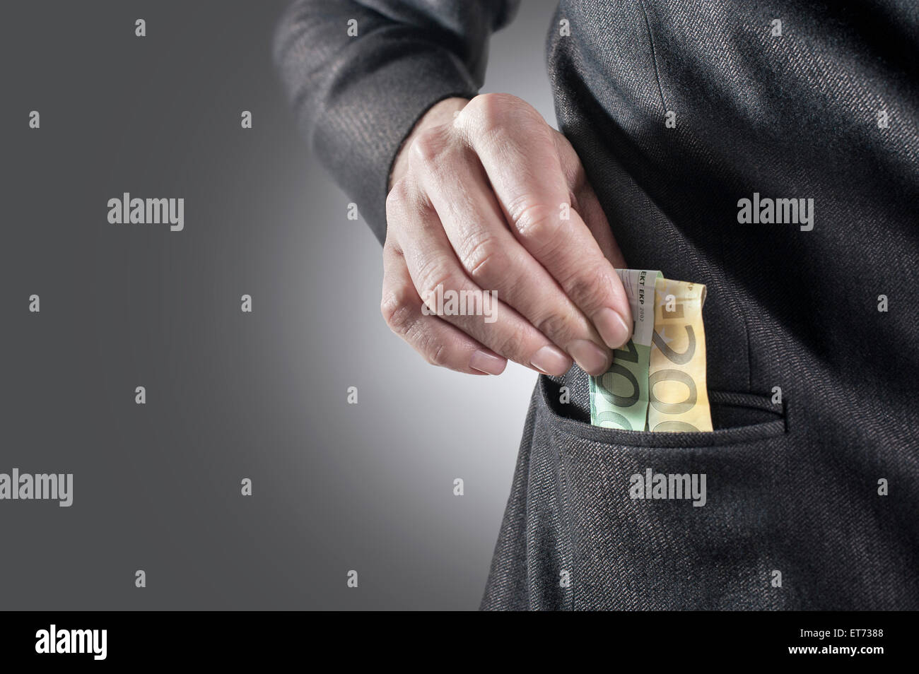 Businessman putting money in his pocket, Bavaria, Germany Stock Photo