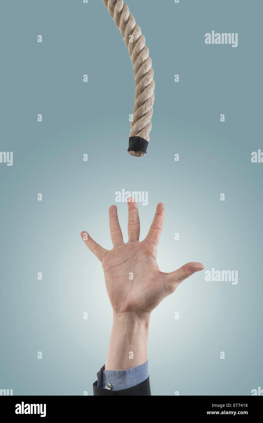 businessman's hand reaching for a rope for salvation, Bavaria, Germany Stock Photo