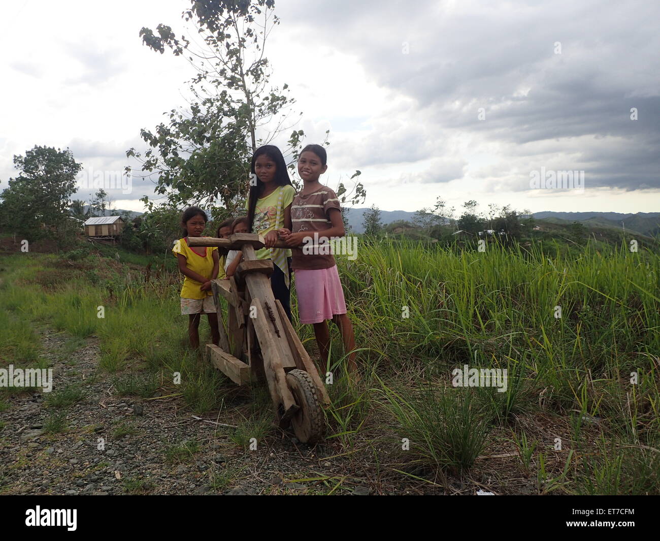 Zamboanga del Sur, Philippines. 12th June, 2015. Young girls playing and enjoying a wooden bicycle on the rough roads of Sitio Lumangking in Dumingag, Zamboanga del Sur which is considered as 'World Day Against Child Labor. Around the world, there are 120 million children between the ages of 5 and 14 are involved in child labor, with boys and girls in this age group almost equally affected. Credit:  Sherbien Dacalanio/Pacific Press/Alamy Live News Stock Photo