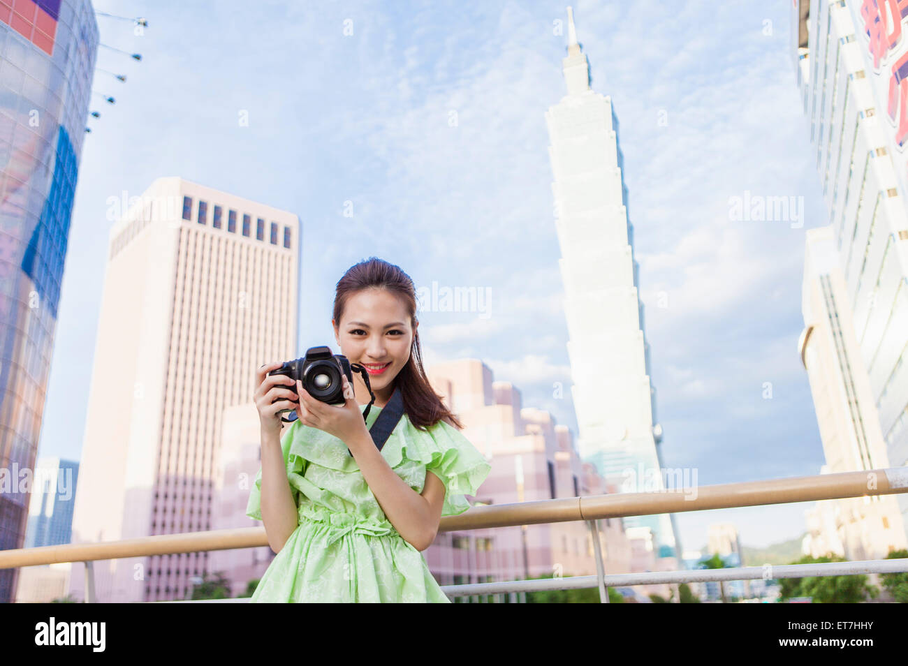 Young woman holding camera and smiling at the camera Stock Photo - Alamy