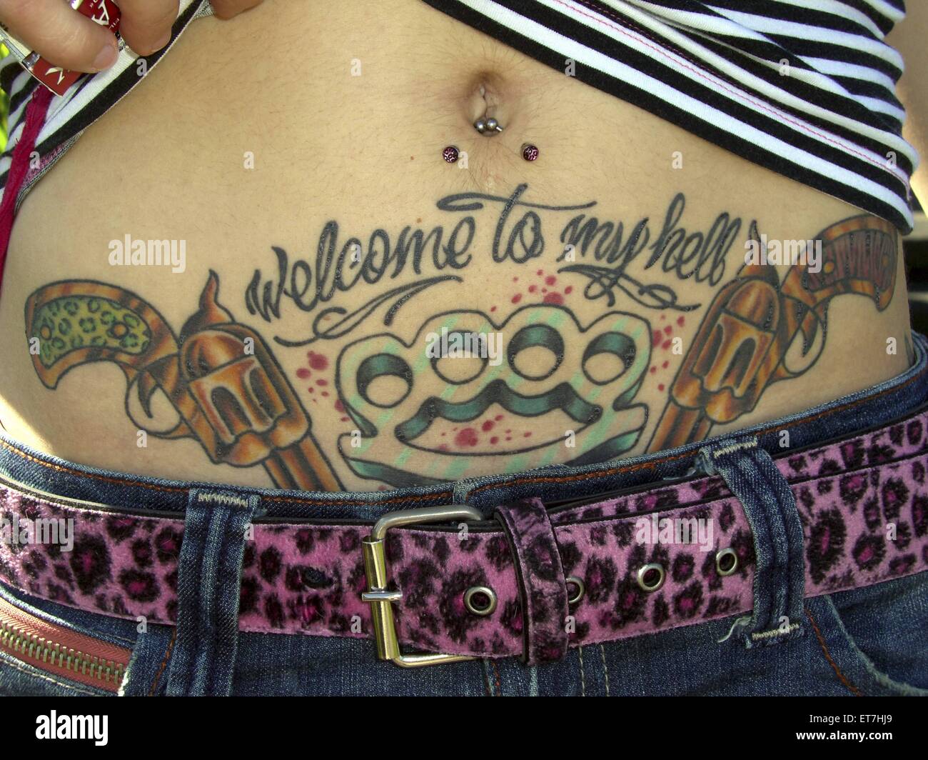 Tattoo mit zwei Pistolen und einem Schlagring auf dem Bauch einer Stock