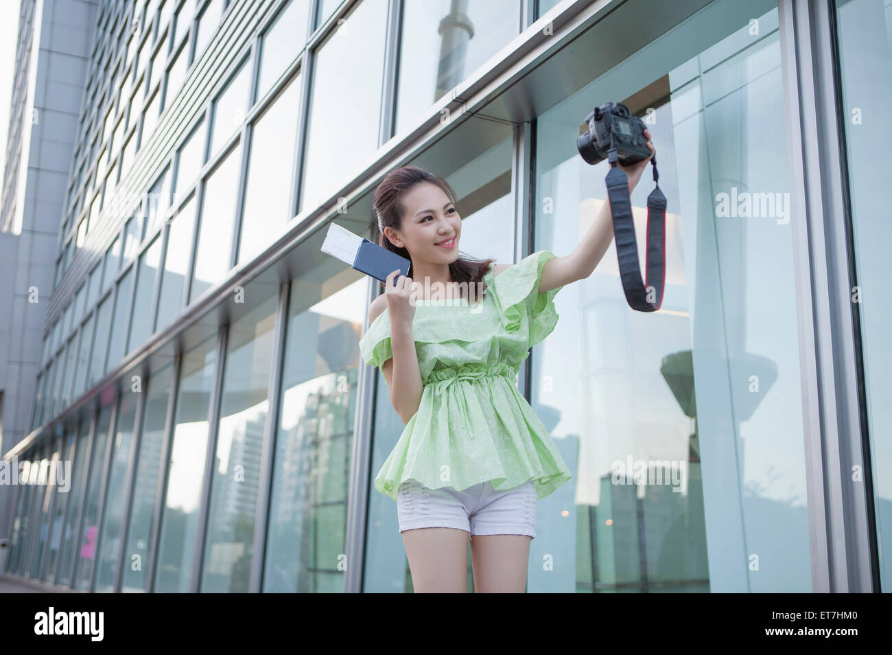 Young woman holding camera and taking photos Stock Photo - Alamy