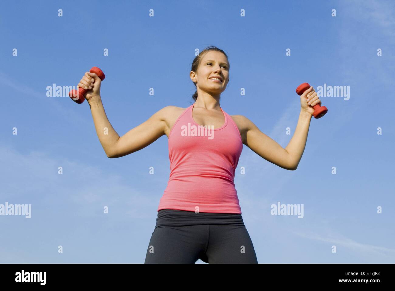 Junge Frau trainiert mit Hanteln in der Natur | butterfly, young woman lifting barbells outdoor, butterfly Stock Photo