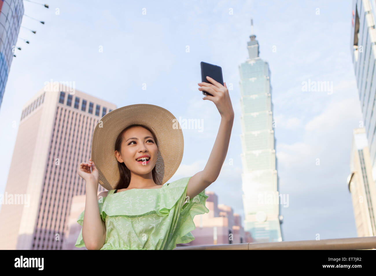 Young woman taking photos with smart phone and smiling Stock Photo