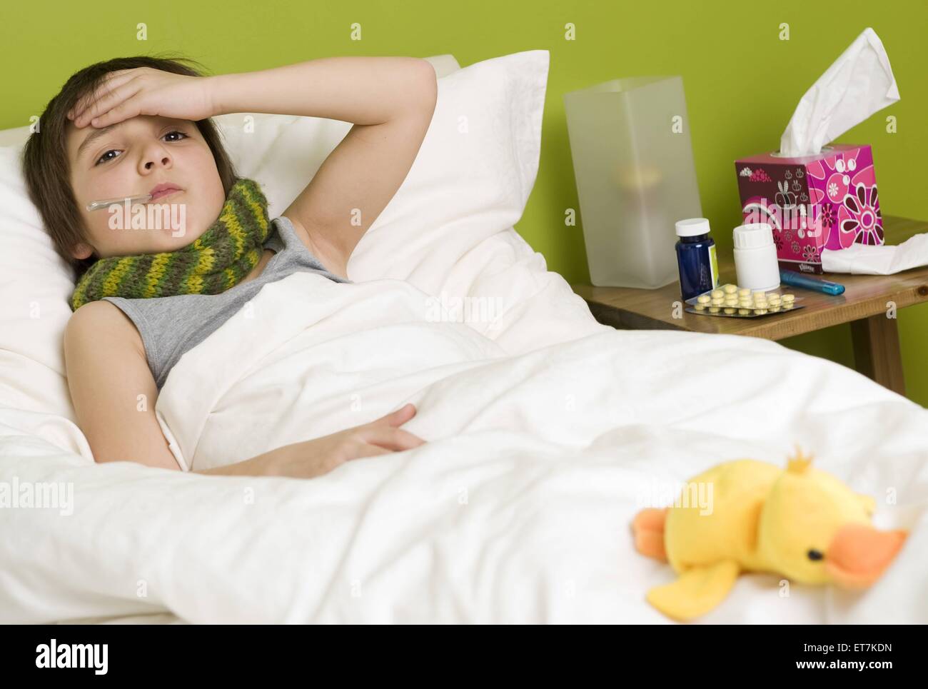 kranker Junge mit Fieberthermometer im Bett | sick boy with fever in bed Stock Photo