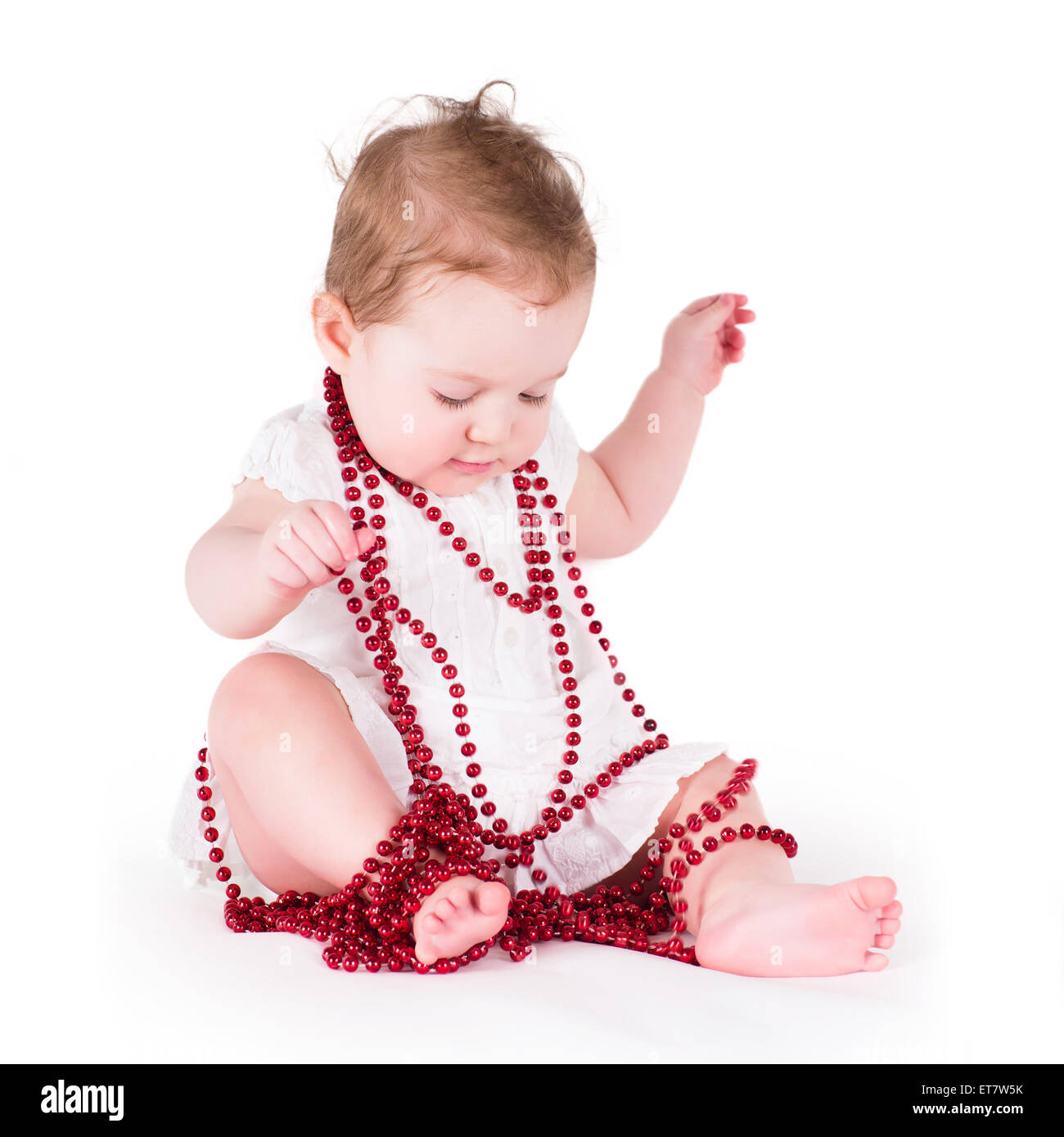 Funny baby girl playing with red pearls Stock Photo