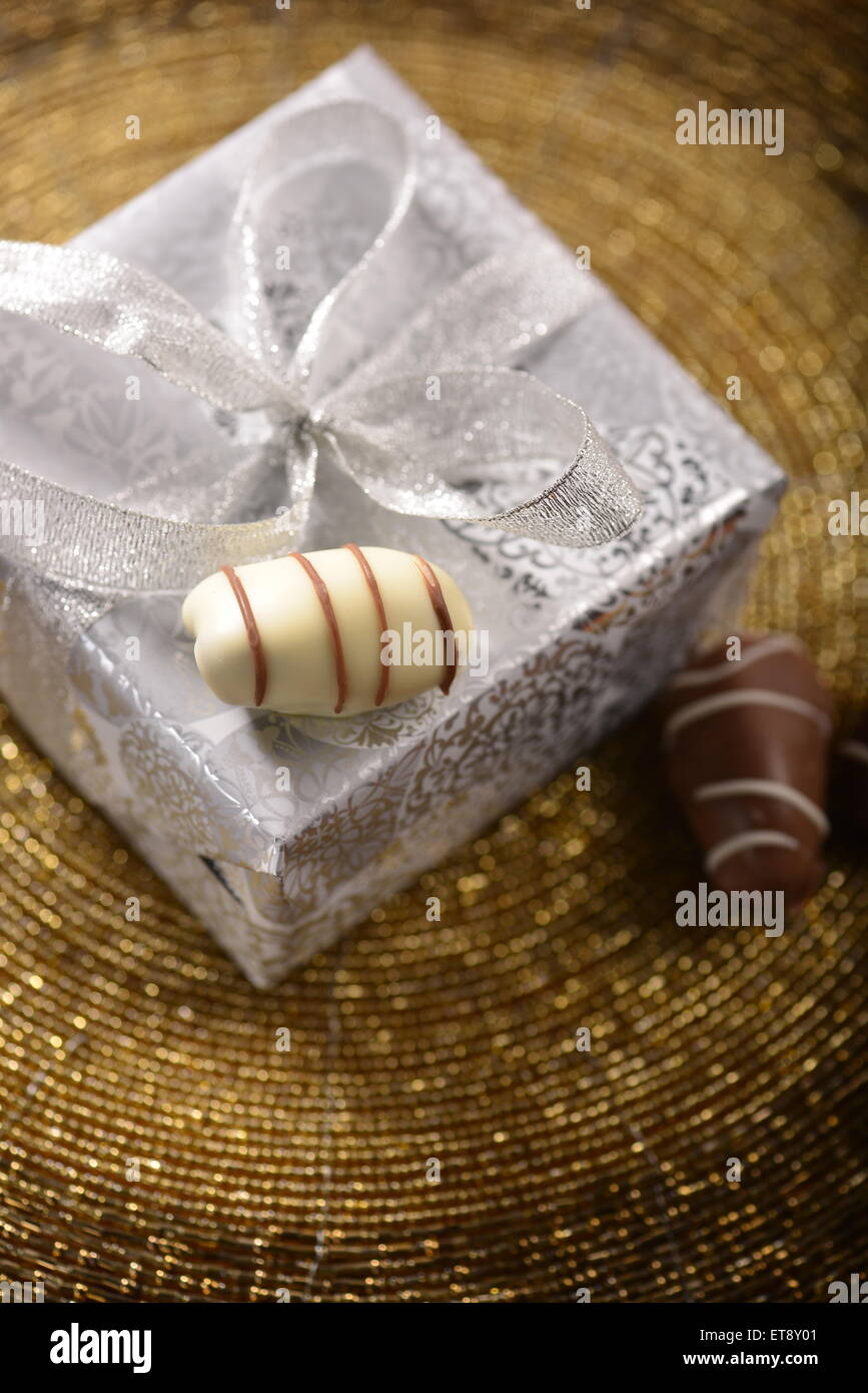 A silver gift box and three date fruit chocolates from top angle. Stock Photo