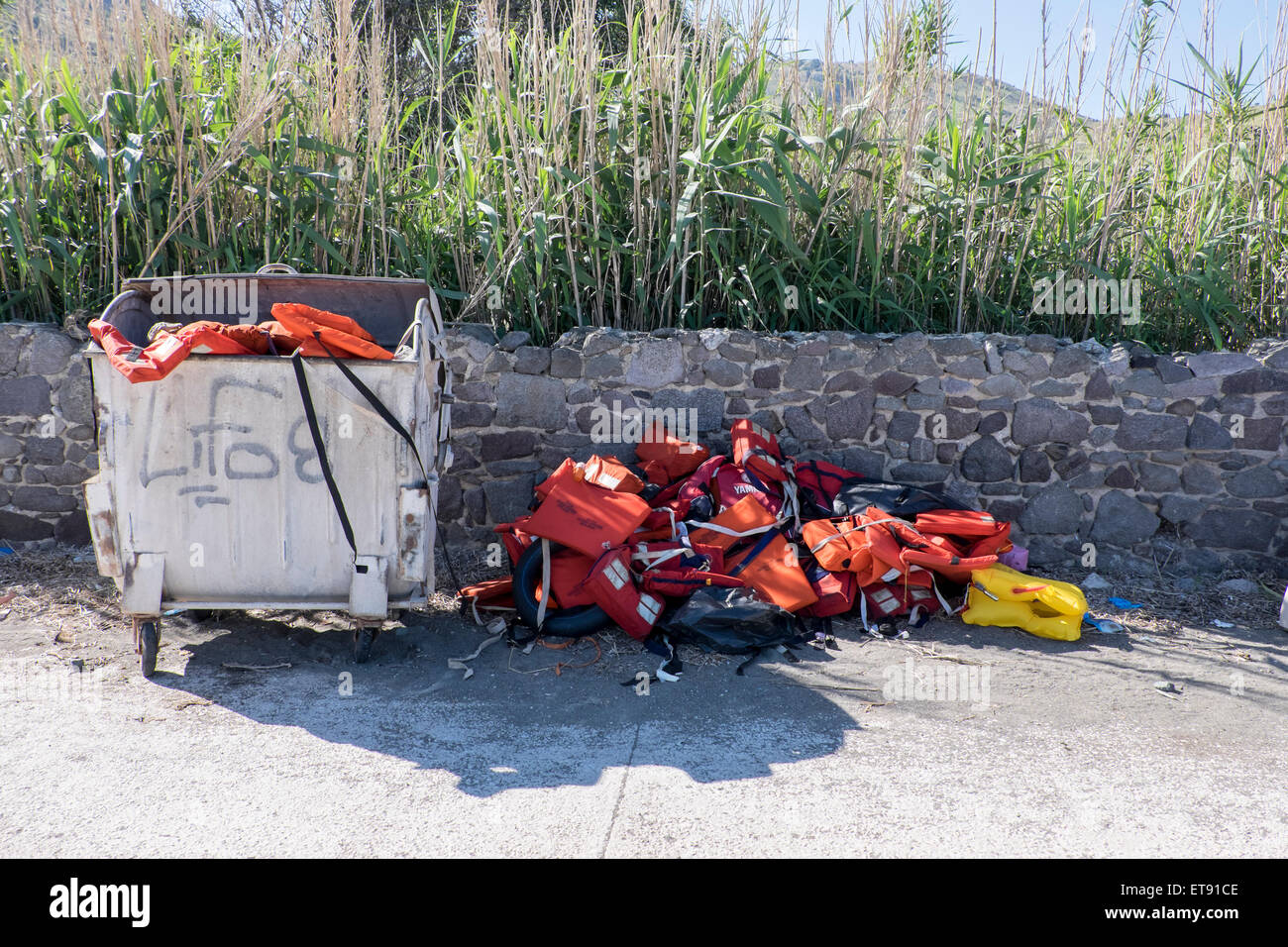 Life vests worn by refugees fleeing Syria and Afghanistan are piled up as trash on a beach in Greece. Stock Photo