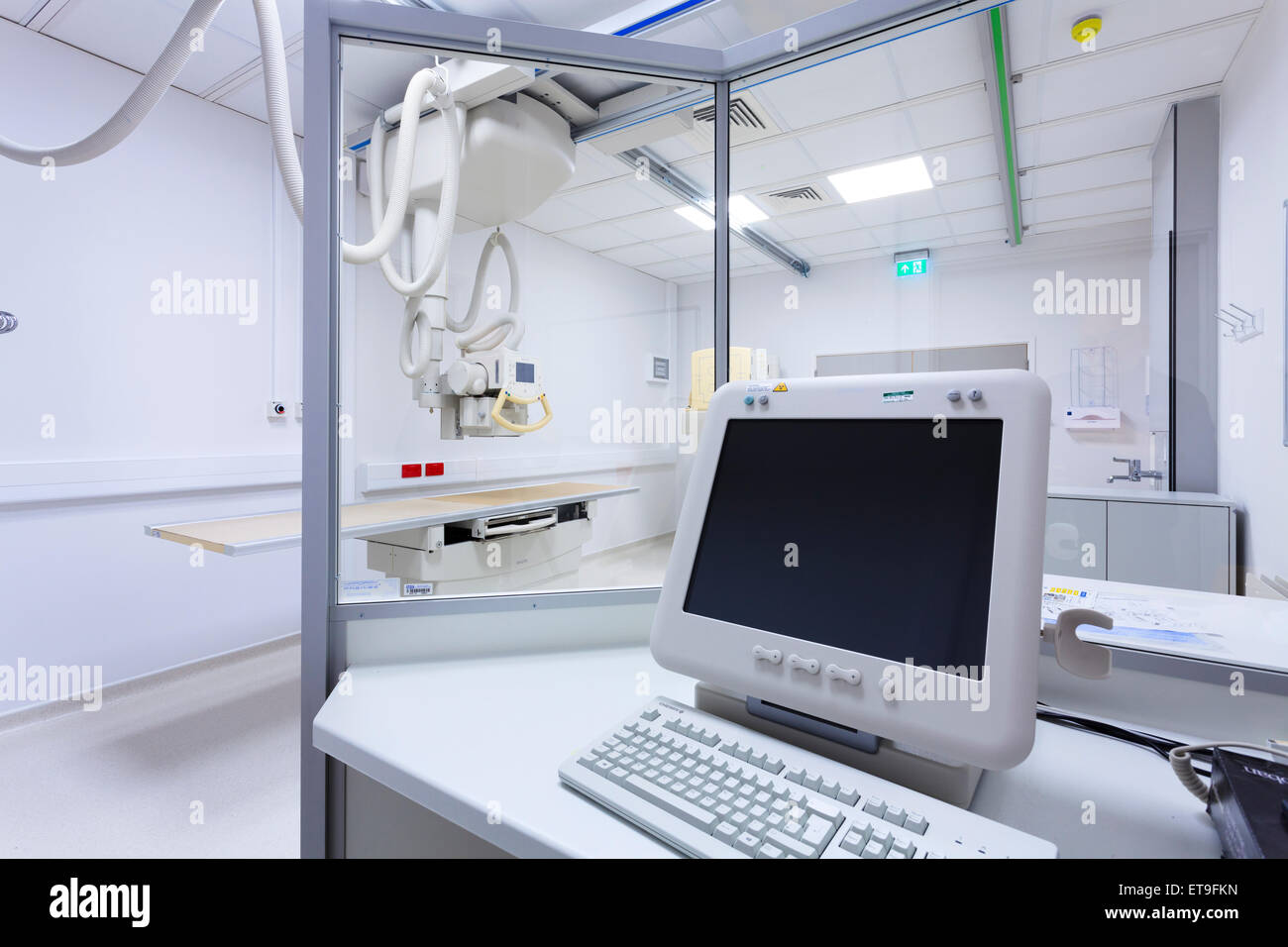 Hospital X-Ray room with monitor screen, protective screen and table without people Stock Photo