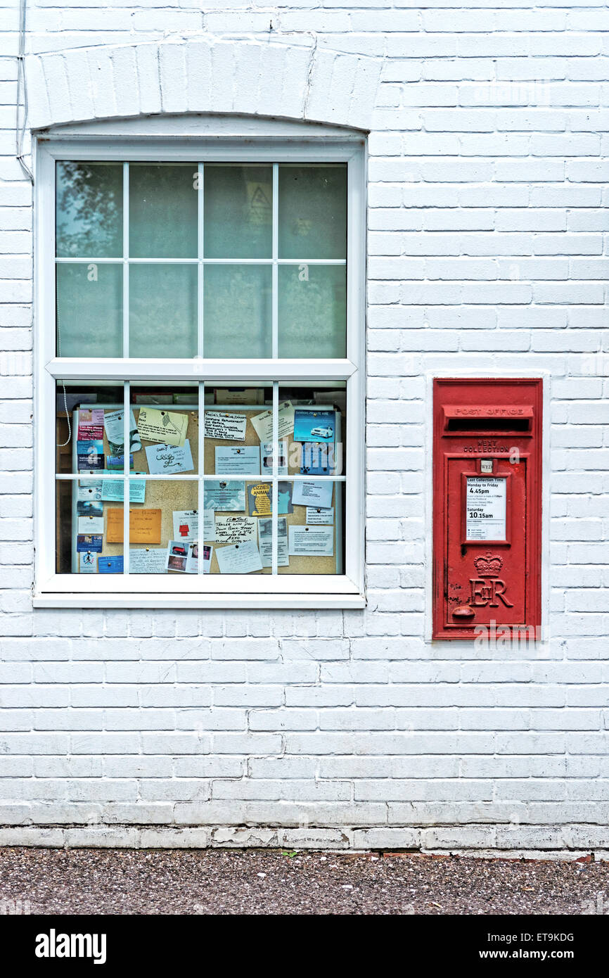 Red postbox outside village store. Stock Photo