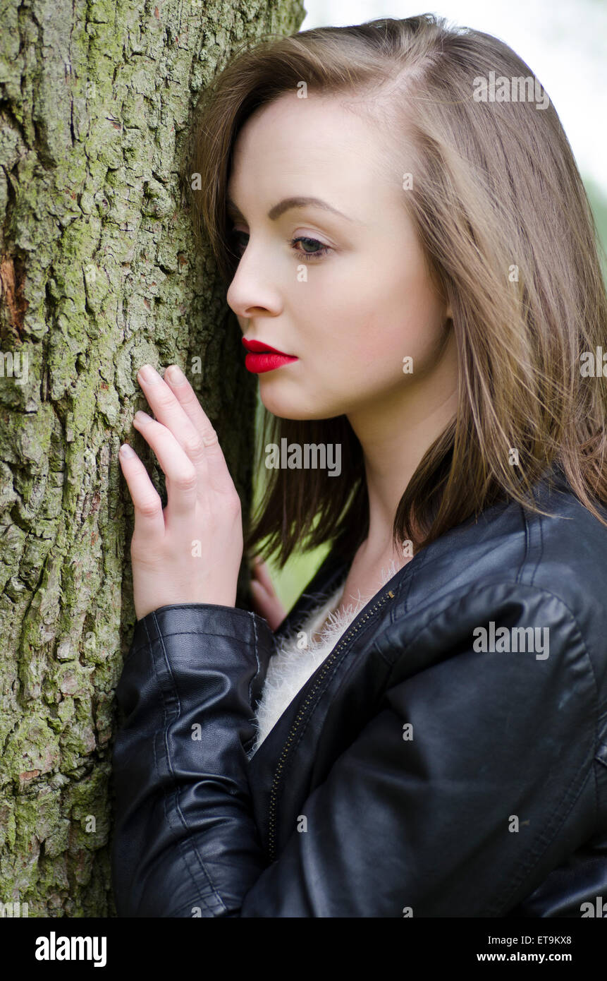 Serious young woman standing by the tree Stock Photo