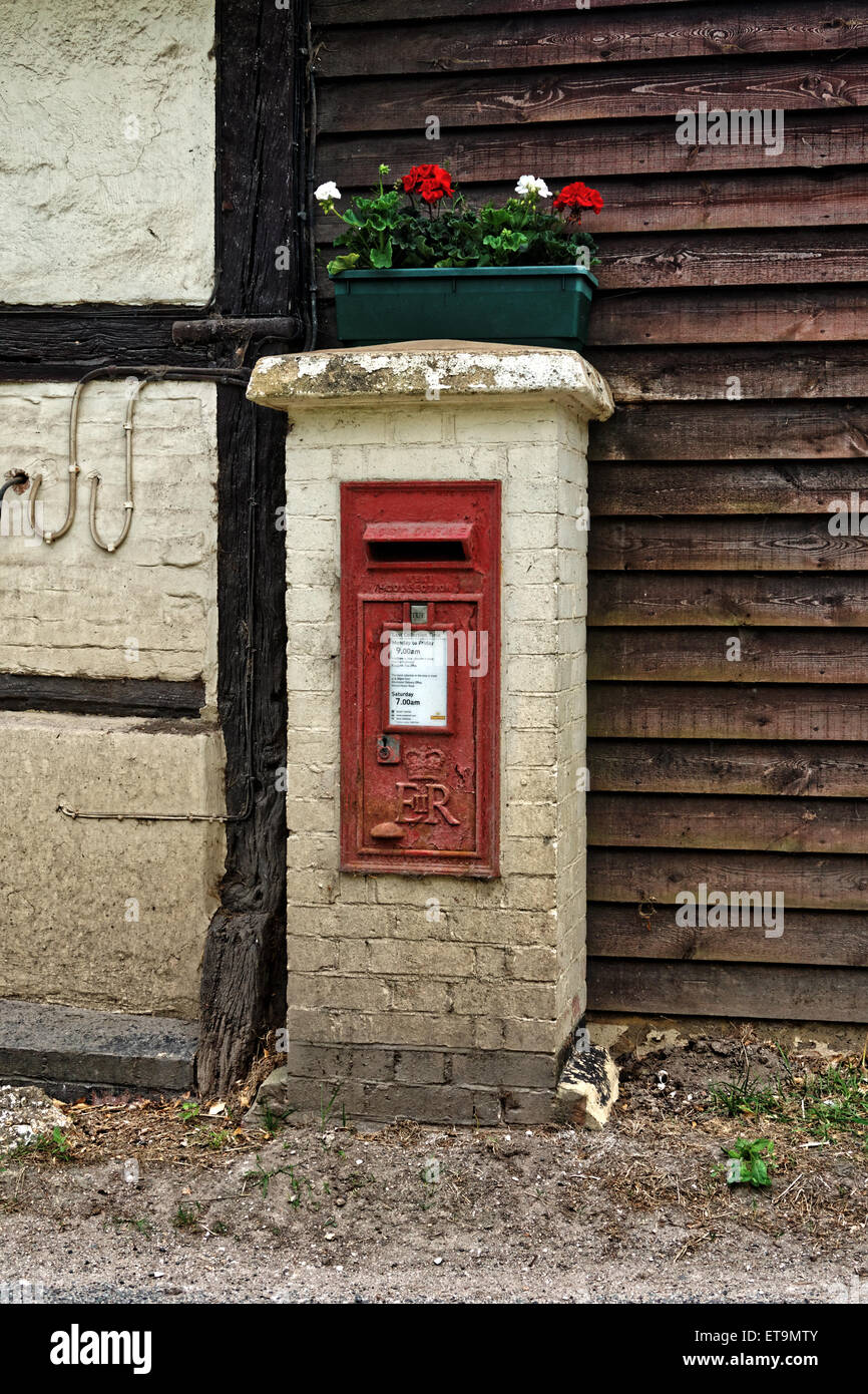 Red postbox with geraniums growing on top. Stock Photo