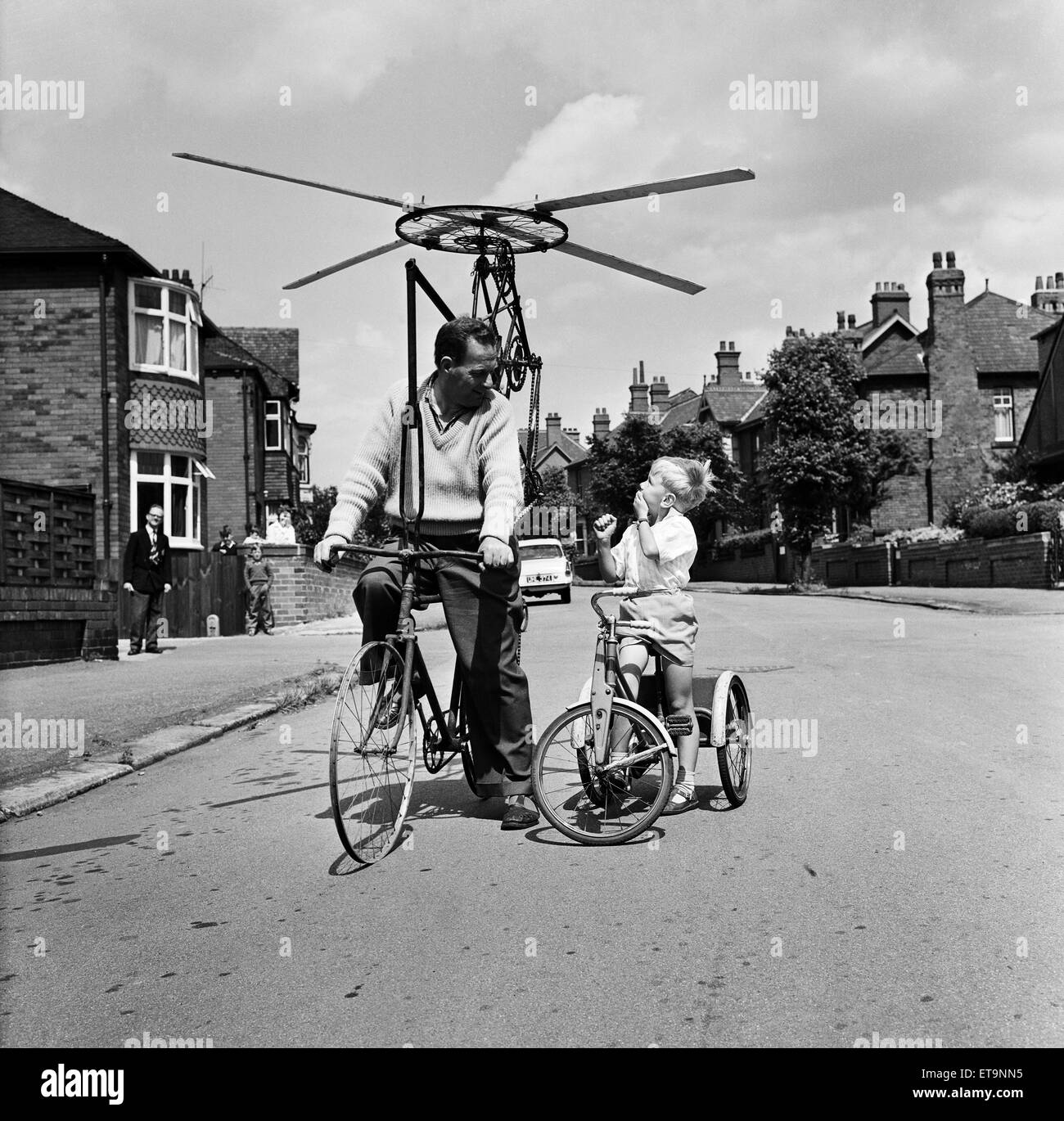 Mr Clifford Davis of Leeds Road Wakefield, tries out his flying machine made from bits of old pedal cycles. Maxwell Hemingway six looks on in wonder at Mr Davis flying machine. West Yorkshire, 25th June 1965. Stock Photo