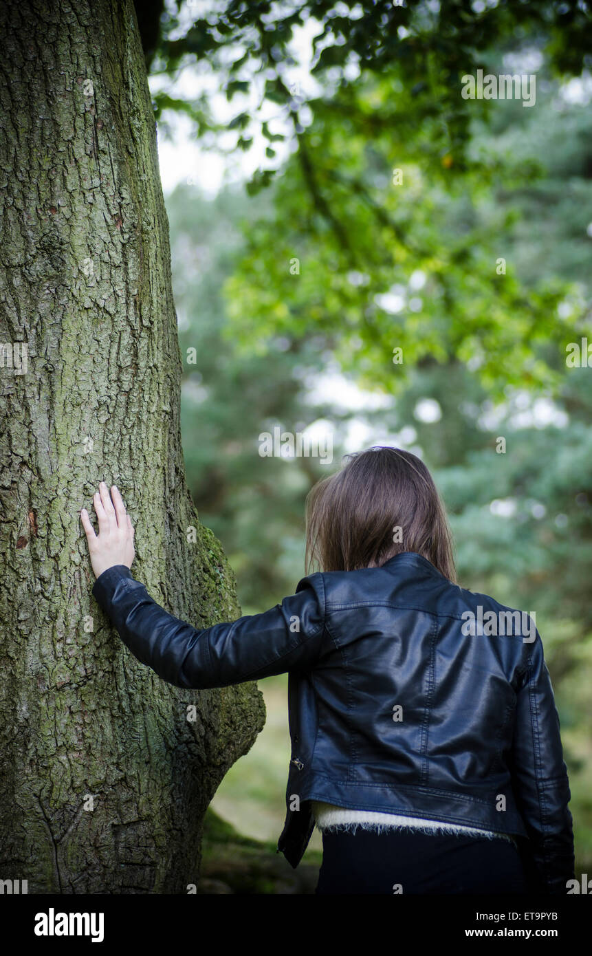 Young woman leaning against a tree Stock Photo