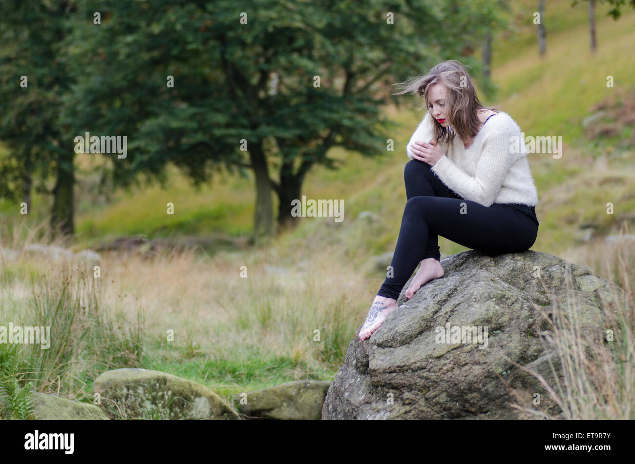 Young woman sat on the rocks Stock Photo
