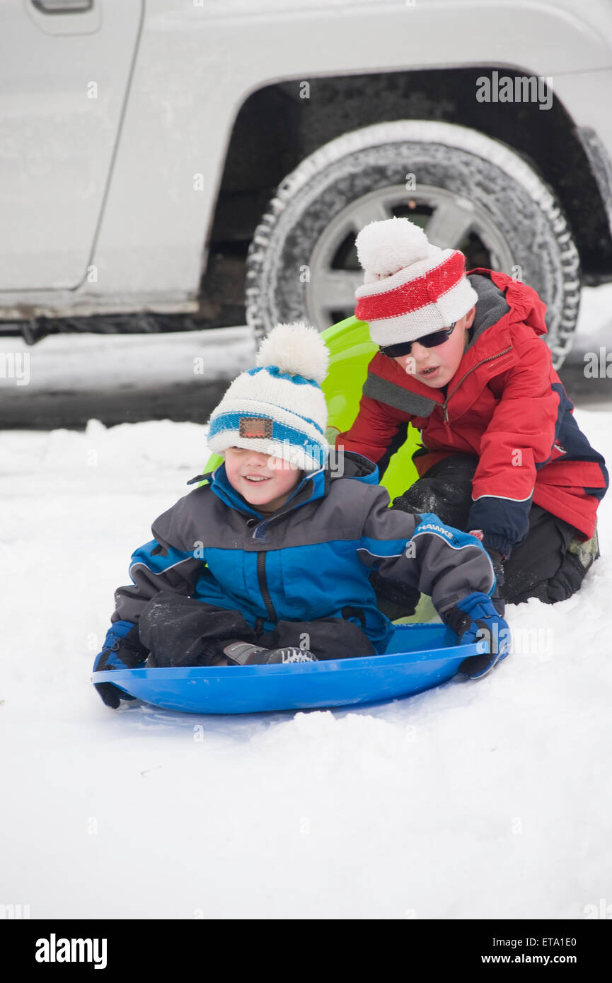 Brothers ages 5 and 8 sledding Stock Photo