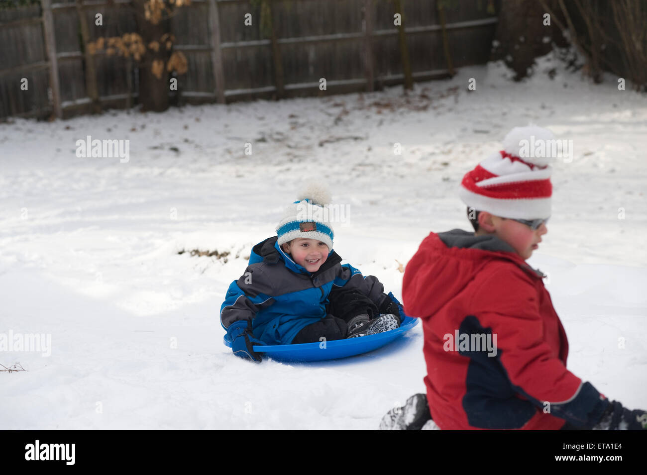 Brothers ages 5 and 8 sledding Stock Photo