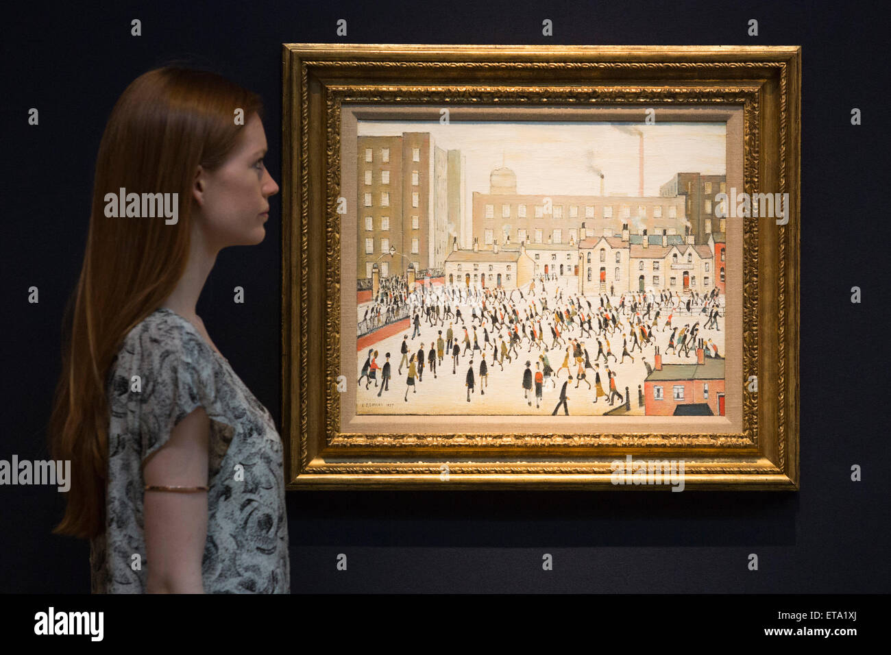A Christie's employee poses with the L.S. Lowry painting 'Going to Work, estimate GBP 700,000-1m. Preview of the highlights of the Christie's Modern British and Irish Art Evening Sale on 25 June 2015 in London. Stock Photo