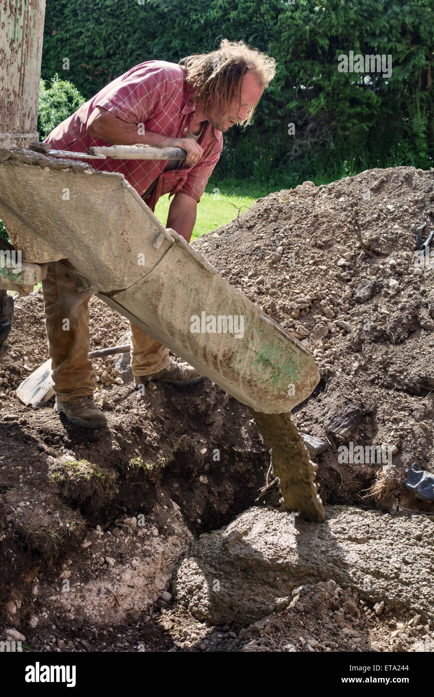 UK. A builder pouring concrete for the foundations of a garden summerhouse Stock Photo