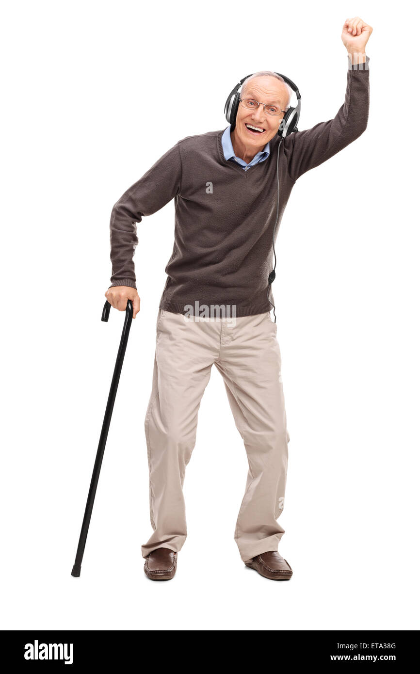 Full length portrait of an overjoyed senior holding a cane and listening to music on headphones isolated on white background Stock Photo